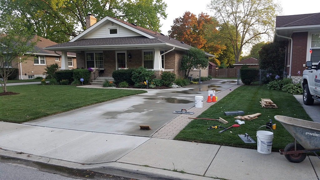 Concrete driveway and walkway work beside a mature Milwaukee-area home